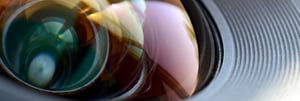 Primer plano de una lente de cámara con reflejos coloridos y detalles nítidos en el cristal, que resaltan la precisión y complejidad del diseño óptico | HOF