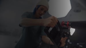 Persona ajustando una cámara profesional con micrófono incorporado en un set de grabación iluminado, preparando equipo para producción audiovisual.